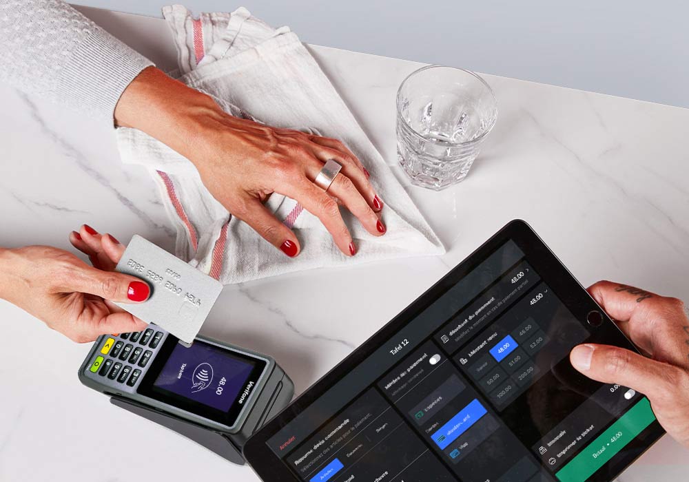 Vrouw met kaart, betaalterminal en iPad met betaling.