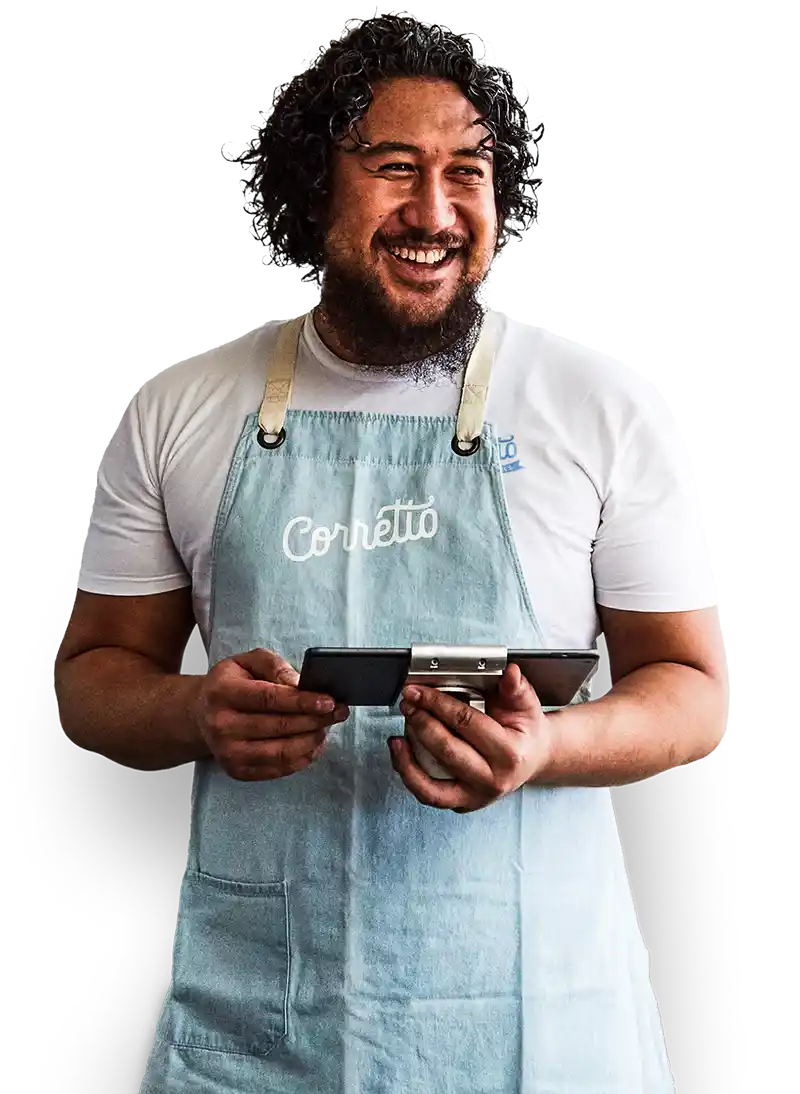 Glimlachende restauranteigenaar in een wit t-shirt en schort gebruikt het Lightspeed Restaurant kassasysteem op een tablet.